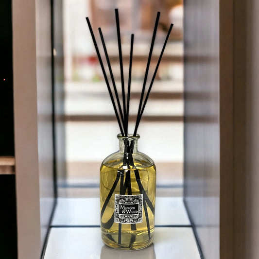 Reed diffuser with black sticks in a glass bottle on a blurred background