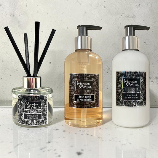A Lime, Basil & Mandarin Reed Diffuser, Hand & Body Wash and Hand & Body Lotion sitting on a white marble surface with a white marble splash back behind.