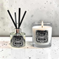 A reed diffuser and a lit scented candle from the brand Marsden & Whittle, both labeled 'Lime, Basil & Mandarin,' displayed on a light speckled surface against a textured light gray wall.