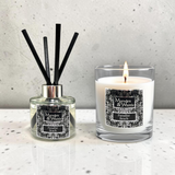 A reed diffuser and a lit scented candle from the brand Marsden & Whittle, both labeled 'Paradise Beach,' displayed on a light speckled surface against a textured light gray wall.