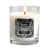A lit white candle in a clear glass jar with a black and chrome ornate label reading 'Marsden & Whittle' and 'Pumpkin Spice'.