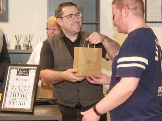 A Marsden & Whittle employee handing over a bag of products to a satisfied customer at the Marsden & Whittle shop in Wrexham.