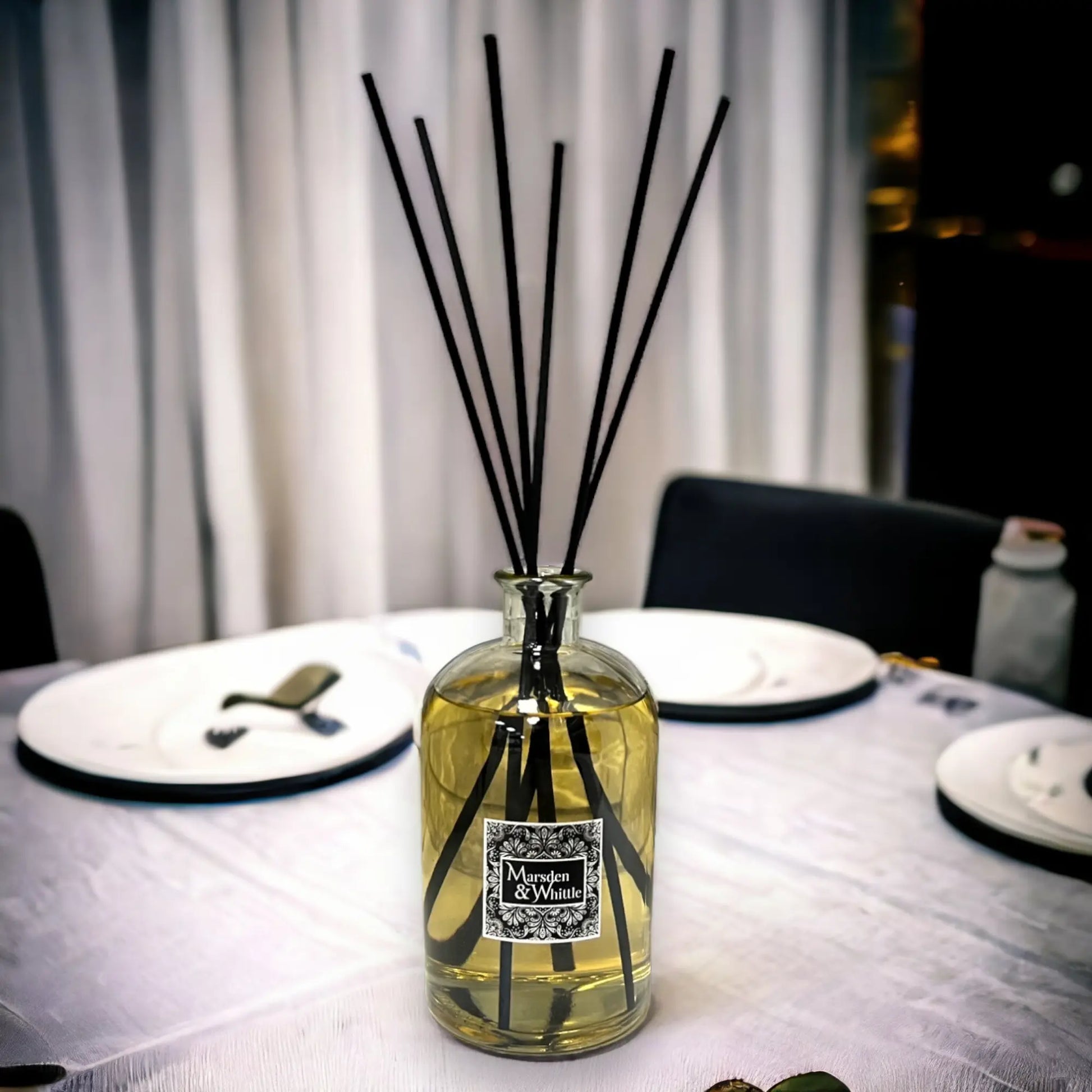 Diffuser bottle with black sticks on a table setting