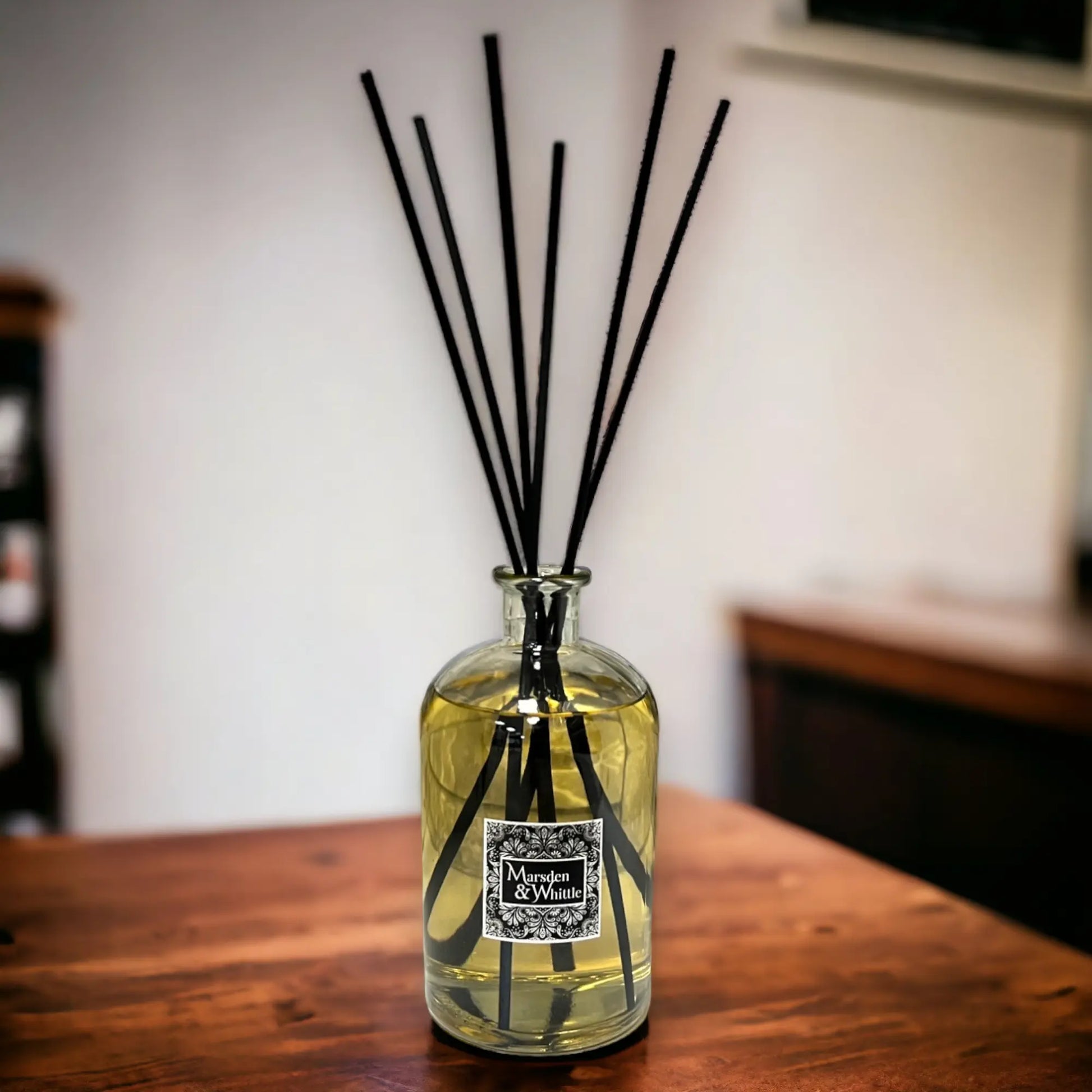 Diffuser bottle with black sticks on a wooden surface