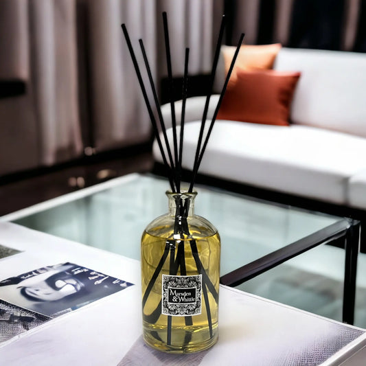 Large diffuser bottle with black reeds on a table in a living room setting